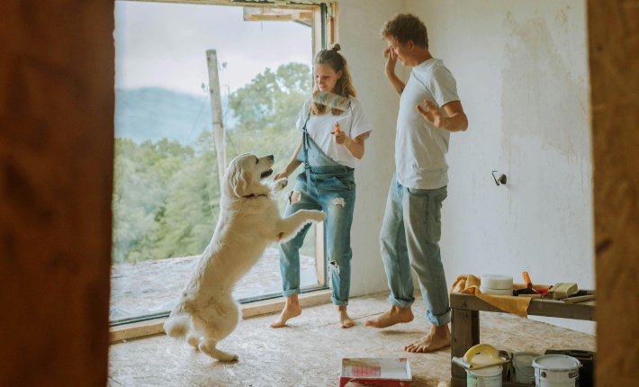 Happy couple painting and smiling with Golden Retriever dog 