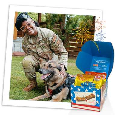 U.S. service member kneeling with a military dog beside Nubz red, white and blue box. 
